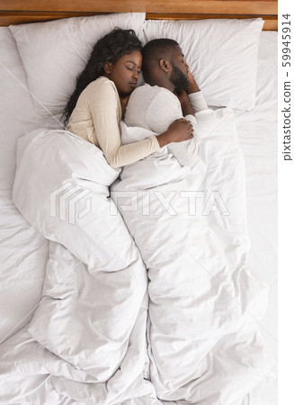 Afro couple hugging while sleeping together in bed, top view 59945914