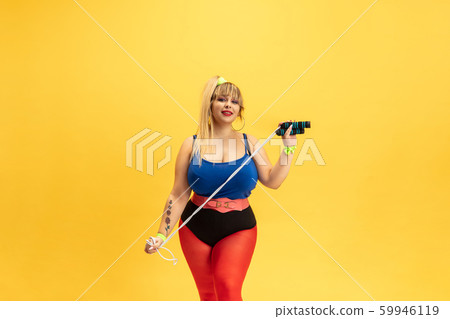 Young caucasian plus size female model's training on yellow background Young caucasian plus size female model's training on yellow background 59946119