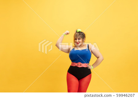 Young caucasian plus size female model's training on yellow background 59946207