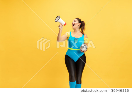 Young caucasian plus size female model's training on yellow background 59946316
