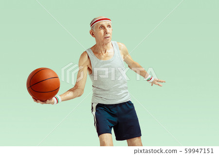 Senior man playing basketball in sportwear isolated on green background Senior man playing basketball in sportwear isolated on green background 59947151