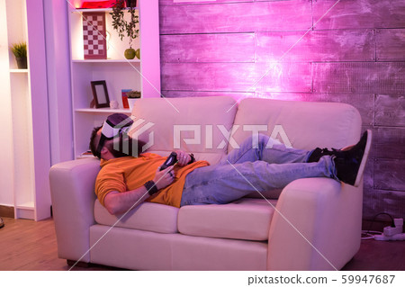 Male sitting on couch with virtual reality goggles 59947687