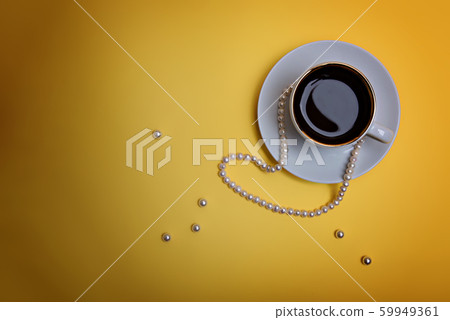 A cup of espresso and pearl beads on a yellow background. A cup of espresso and pearl beads on a yellow background. 59949361