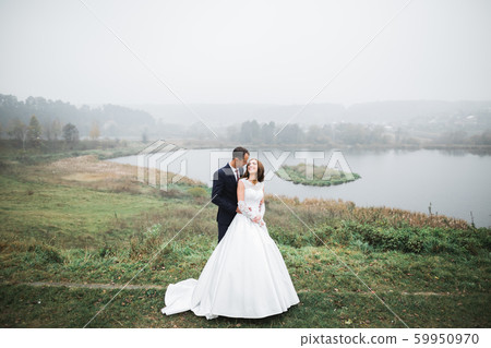 Beautiful romantic wedding couple of newlyweds hugging in park Beautiful romantic wedding couple of newlyweds hugging in park 59950970