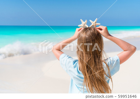 Adorable little girl with starfish on white empty beach 59951646