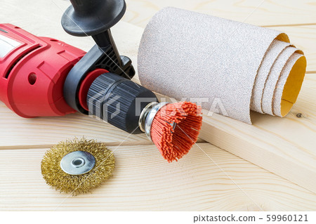 Red drill, sandpaper and abrasive brushes with nylon and metal wire on a wooden surface. 59960121
