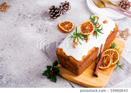 Fruit loaf cake dusted with icing, nuts and dry orange on stone background. Christmas and Winter Holidays Fruit loaf cake dusted with icing, nuts and dry orange on stone background. Christmas and Winter Holidays 59960643