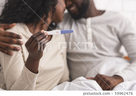 Happy african american couple showing pregnancy test with positive result 59962478