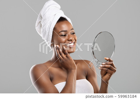 Beautiful african woman holding mirror and touching her perfect soft skin Beautiful african woman holding mirror and touching her perfect soft skin 59963184