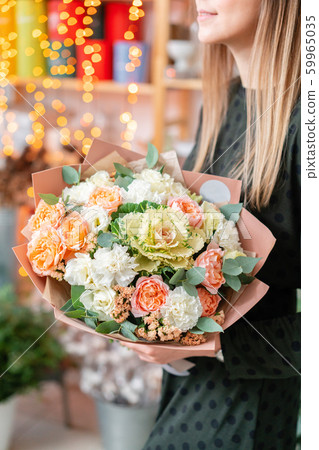 European floral shop. Beautiful bouquet of mixed flowers in womans hands. the work of the florist at 59965035