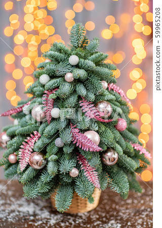 Beautiful small Christmas tree on wooden table. Happy mood. Garland lamp bokeh on background Beautiful small Christmas tree on wooden table. Happy mood. Garland lamp bokeh on background 59965208