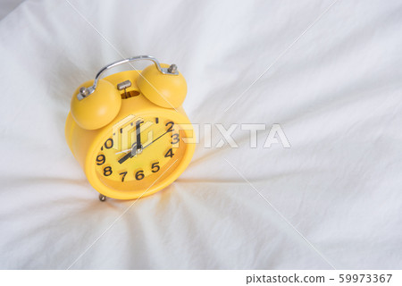 Yellow Alarm clock at 8 am on the bed Yellow Alarm clock at 8 am on the bed 59973367