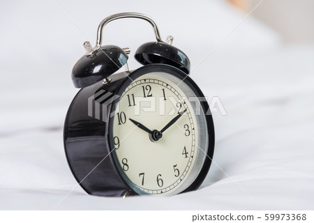 Black Alarm clock at 8 am on the bed Black Alarm clock at 8 am on the bed 59973368
