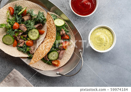 Two mexican pork carnitas tacos with sauces and vegetables. 59974184