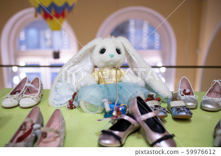 White fluffy hare toy among children's shoes White fluffy hare toy among children's shoes 59976612