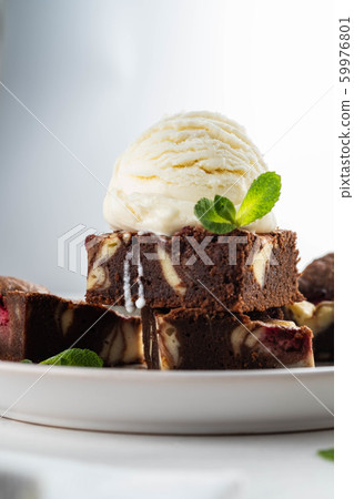 Chocolate brownie with vanilla ice cream, rasberry and mint on a white background. Copy space. Chocolate brownie with vanilla ice cream, rasberry and mint on a white background. Copy space. 59976801