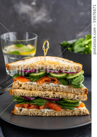 Sandwiches with cream cheese, salmon and spinach on a dark background. 59976871