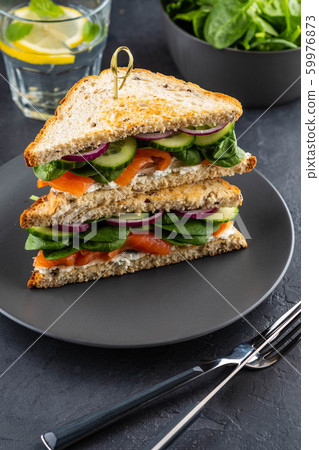 Sandwiches with cream cheese, salmon and spinach on a dark background. 59976873