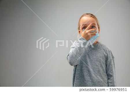 Caucasian girl wearing the respiratory protection mask against air pollution and dusk on grey studio background 59976951