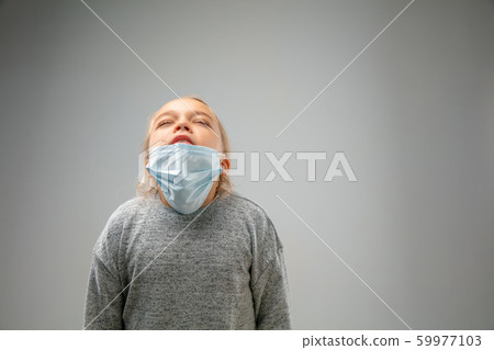 Caucasian girl wearing the respiratory protection mask against air pollution and dusk on grey studio background 59977103