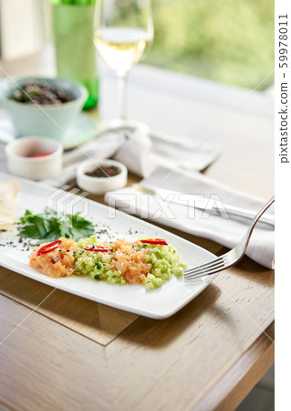 Closeup of salted and smoked salmon or trout fillet on a fork. Salmon tartare with cucumber and 59978011