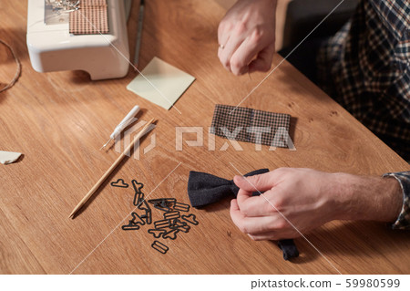 Tailor makes bow ties of woolen fabric. Work with sewing machine in a textile studio. 59980599