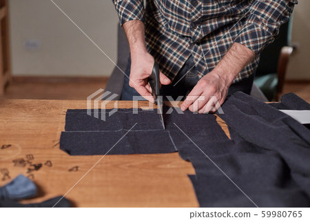 Closeup Tailor cutting wool fabric. the line pattern. Craftsman Makes rectangular blanks for Bow Closeup Tailor cutting wool fabric. the line pattern. Craftsman Makes rectangular blanks for Bow 59980765