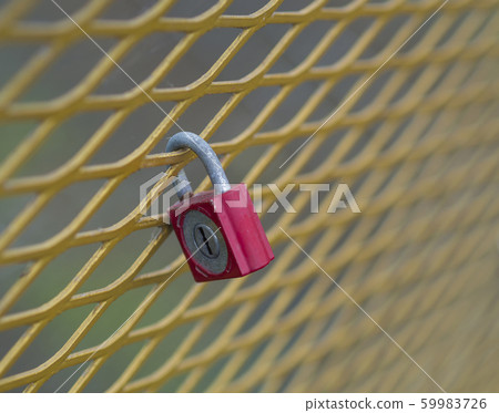 old red lock hanging locked on the yellow metal 59983726