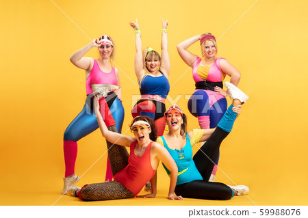 Young caucasian plus size female models training on yellow background 59988076