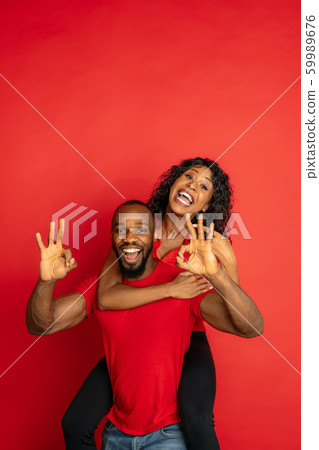 Young emotional african-american man and woman on red background 59989676