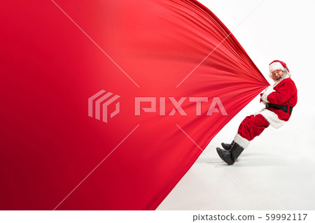 Santa Claus pulling huge bag full of christmas presents isolated on white background 59992117