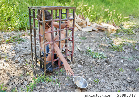 child through the bars of a steel cage reaches child through the bars of a steel cage reaches 59993318