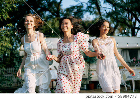 Happy multi ethnic women running and having fun together outdoors during a picnic. 59994778