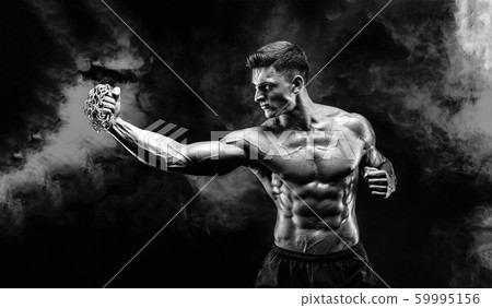 Serious muscular fighter doing the punch with the chains braided over his fist. Serious muscular fighter doing the punch with the chains braided over his fist. 59995156