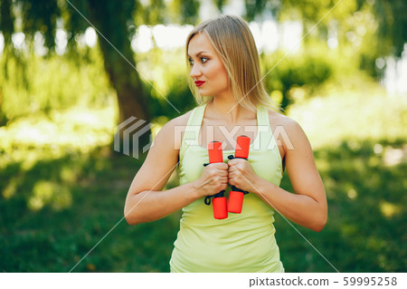 A beautiful girl is engaged in morning exercise in the park. A beautiful girl is engaged in morning exercise in the park. 59995258