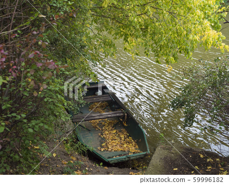 Old rowing boat with fallen leaves on the river 59996182