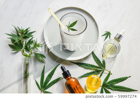 Cannabis milk, leaf of cannabis and a bottle of CBD Oil and tincture on the kitchen table. Top view, flat lay Cannabis milk, leaf of cannabis and a bottle of CBD Oil and tincture on the kitchen table. Top view, flat lay 59997274