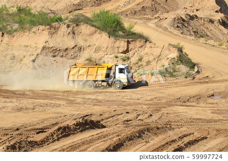 Big yellow dump truck transporting sand in an open-pit quarry 59997724