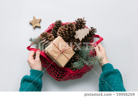Woman hands holding mesh bag with Christmas zero 59998209