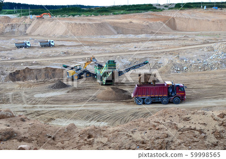 Wheel front-end loader loads sand into a dump truck. 59998565
