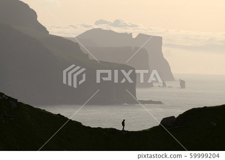 Man silhouette on background of famous Risin og Kellingin rocks Man silhouette on background of famous Risin og Kellingin rocks 59999204