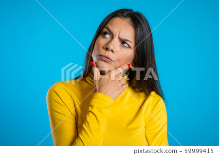 Thinking woman looking around on blue background. Worried contemplative face expressions. Beautiful young hispanic model. 59999415