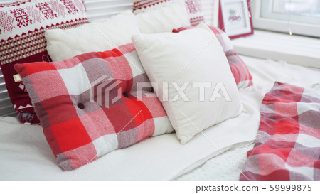 Winter Christmas decorations. Red White pillows on the bed 59999875