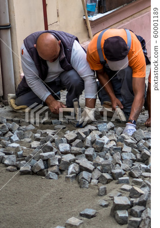 Team Of Construction Workers Building Pavement With Cobblestones 60001189