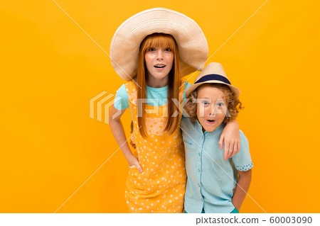 Two surprised red-haired brother and sister are looking in summer hats, are looking at the camera on 60003090