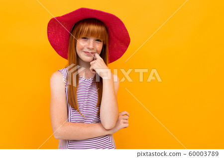 European red-haired girl in a red panama on a yellow background 60003789