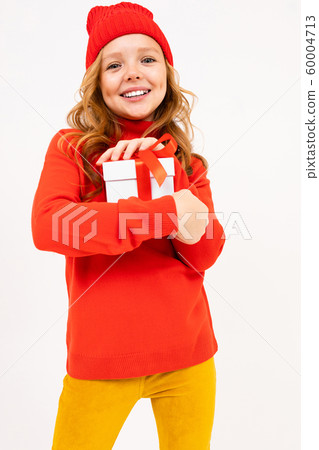 girl in a red hat holds a gift on a white studio background 60004713