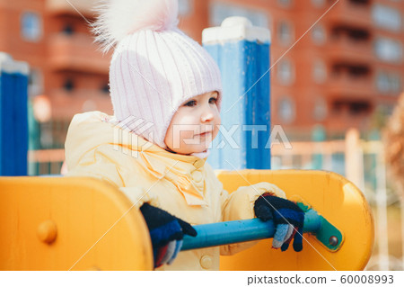 A little girl playing on the Playground of the children's town. a small child rides down the hill, on the carousel, climbs the ropes. Entertainment industry concept, family day, children's parks A little girl playing on the Playground of the children's town. a small child rides down the hill, on the carousel, climbs the ropes. Entertainment industry concept, family day, children's parks 60008993