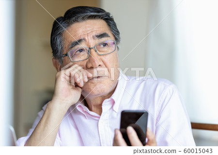 Senior man looking at smartphone Looking far away Senior man looking at smartphone Looking far away 60015043