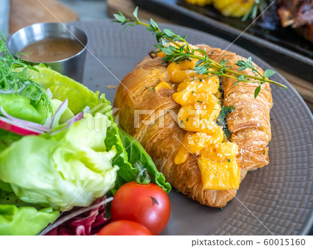 Warm cooked croissant with spinach inside topping with cream cheese, served with vegetable salad Warm cooked croissant with spinach inside topping with cream cheese, served with vegetable salad 60015160